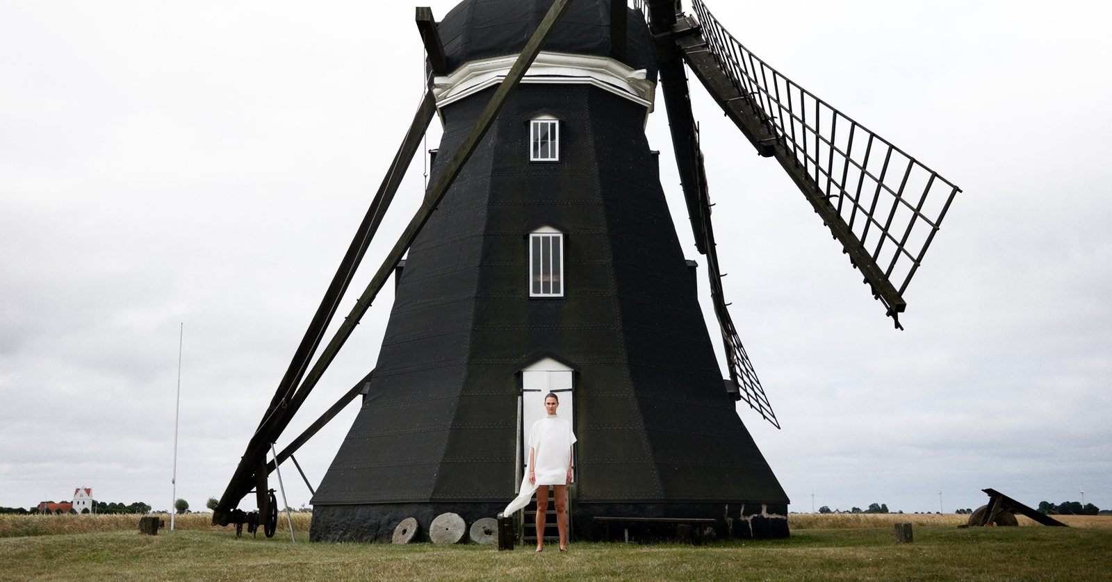 A model in white before the black windmill, wearing D'AVENIR